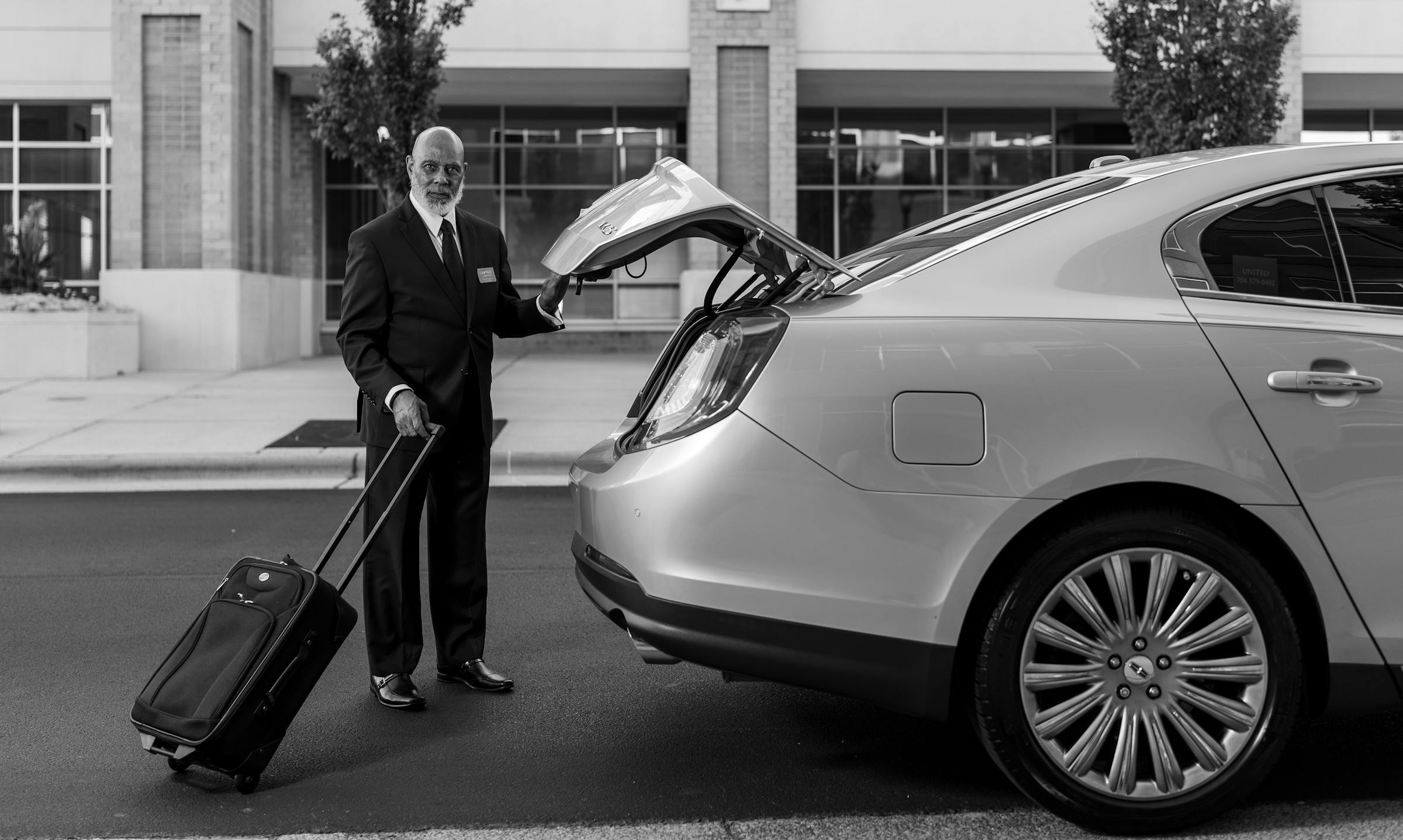 Chauffeur loading luggage at the trunk of a sedan